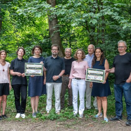 Eine Gruppe von Frauen und Männern stehen im Wald und halten Plakate